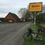 Wacken - Ortsschild mit Gravelbike - Nord-Ostsee-Kanal-Radweg.