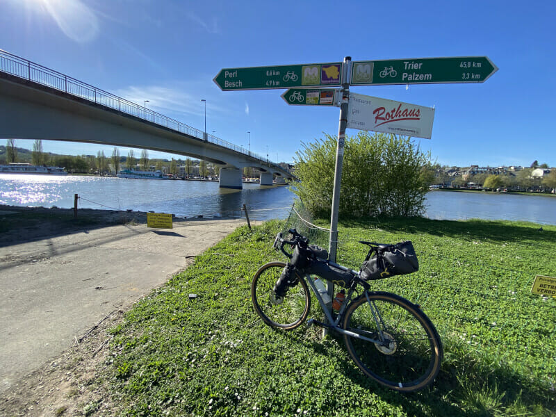Nennig gegenüber von Remich mit Gravelbike und Wegweiser – Moselradweg